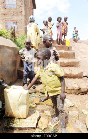 Children collect water from an unclean government water source in the Kosovo slum area of Kampala city in Uganda. Stock Photo