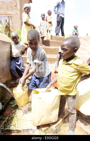 Children collect water from an unclean government water source in the Kosovo slum area of Kampala city in Uganda. Stock Photo