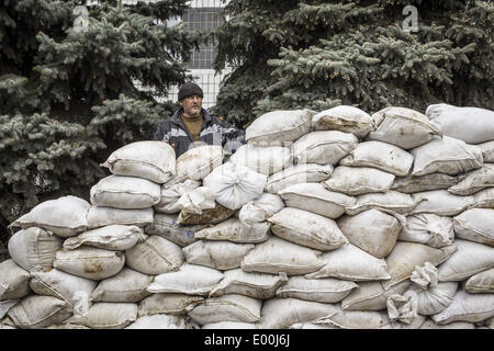 Kostantinovka, Donetsk, Ukraine. 28th Apr, 2014. Men help to form a barricade as pro-Russian armed men in military fatigues stand guard outside a regional administration building seized in the night by pro-Russian separatists, in the eastern Ukrainian city of Kostyantynivka, on April 28, 2014. Kostyantynivka has 80,000 inhabitants and is located mid-way between the flashpoint town of Slavyansk and the regional hub city of Donetsk, both of which are also under the control of insurgents. Stock Photo