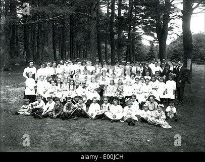 Schoolchildren in Keene, New Hampshire, participate in a field trip led by their teachers. The group is seen outdoors surrounded by trees, engaging in an educational activity as part of their school outing. Stock Photo