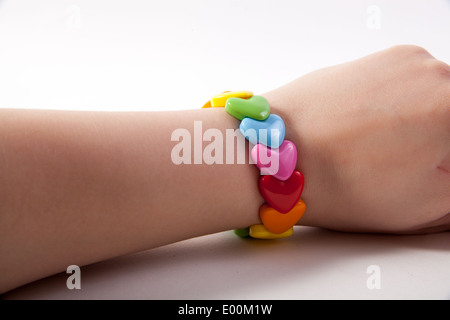 A 1980s retro multi-coloured rainbow plastic stretch heart bracelet on a caucasian girl Stock Photo
