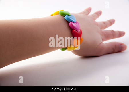A 1980s retro multi-coloured rainbow plastic stretch heart bracelet on a caucasian girl Stock Photo