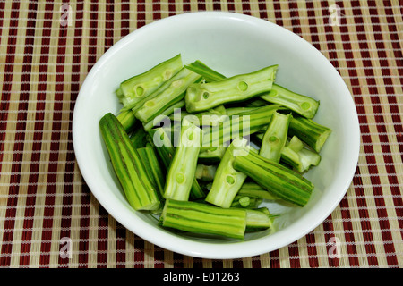 Drumstick cut into pieces for curry, in a white porcelain bowl on a table mat. Stock Photo