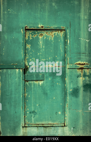 A cast iron industrial green rusting old warehouse door. Stock Photo