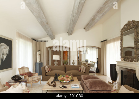 Wide shot of sitting room showing sloping ceiling with large beams and glimpse through archway to dining room  Belleview Villa Stock Photo