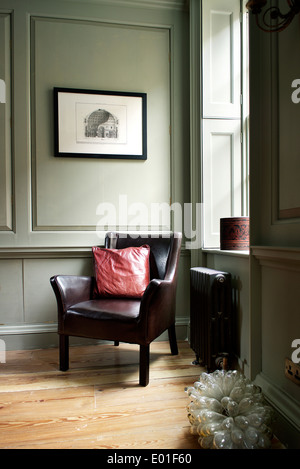First floor living room, corner detail. Leather chair in corner by panelled walls and shuttered window Stock Photo