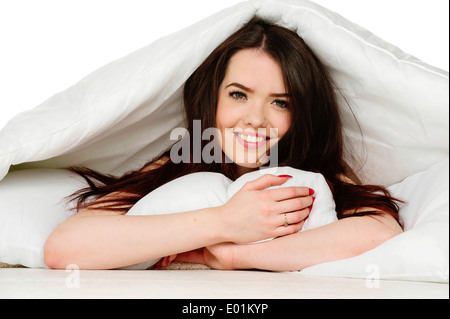 Woman laid in bed smiling at the camera Stock Photo
