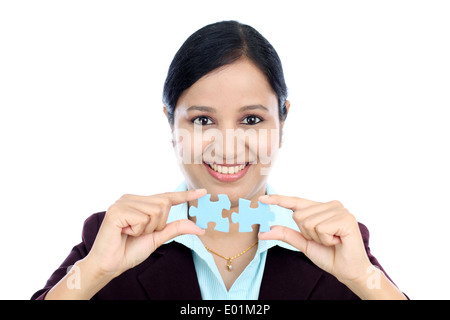 Young Indian business woman joining two jigsaw puzzle pieces against white background Stock Photo