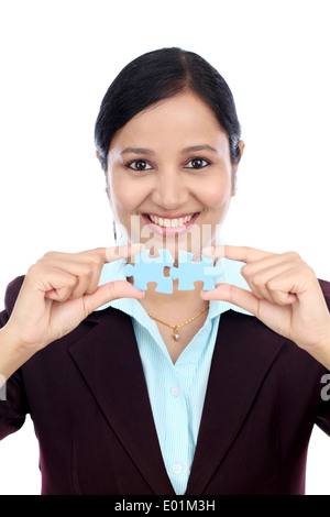 Young Indian business woman joining two jigsaw puzzle pieces against white background Stock Photo