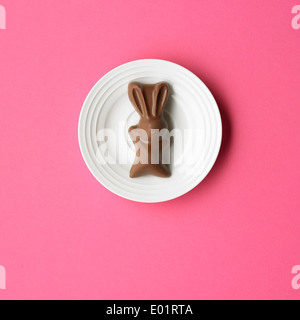 Chocolate bunny on a white plate, pink backgound Stock Photo