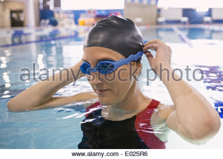 Woman putting on goggles in swimming pool