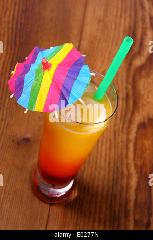 Red, yellow cocktail with lemon, straw, umbrella deco, top view Stock Photo