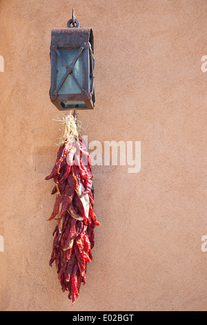 Ristra of dried chili peppers hanging on adobe wall in Santa Fe, New Mexico Stock Photo
