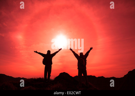 The Silhouette of two man with success gesture standing on the top of mountain Stock Photo