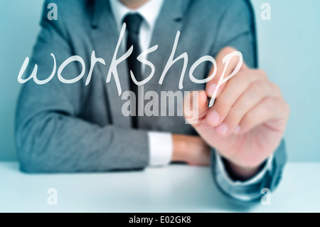 man wearing sitting in a desk writing the word workshop in the foreground Stock Photo