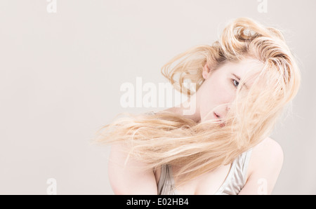 Young beautiful blonde woman with long hair in front of her face. Showing expression of cool  attitude and personality. Stock Photo