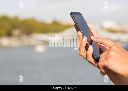 Female Close up of hands mobile phone houseboat seine bridge message sms e-mail