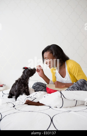 A young girl and her small black dog on a bed. Stock Photo