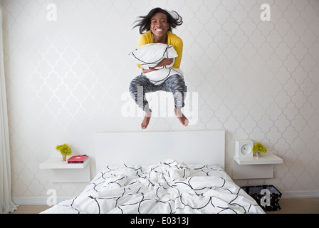 A young girl jumping high in the air above her bed. Stock Photo