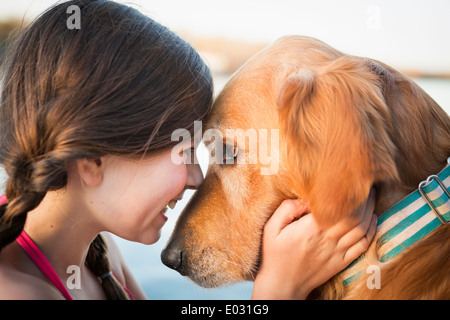 A young girl and a golden retriever dog nose to nose. Stock Photo