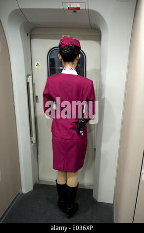 A female train attendant stands at the door of a high speed train as it travels on its way to from Shijiazhuang to Bejing, China, 13 April 2014. Photo: Tim Brakemeier/dpa Stock Photo