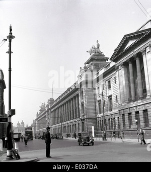 1950s, historical, a view of the grand victorian columed buildings in Kingston upon Hull city centre as a policeman directs motor traffic. We see motor cars of the era and a Corporation Transport doubledecker motorbus in the distance. Stock Photo