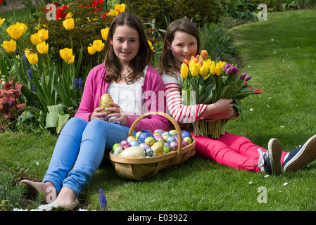 Easter egg hunt girls with their chocolate eggs and Spring flowers Stock Photo