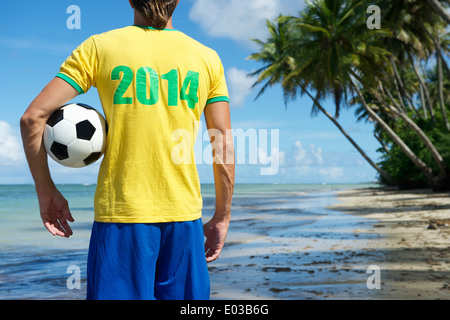 Brazilian football player in 2014 shirt holding soccer ball on remote beach in Nordeste Bahia Brazil Stock Photo