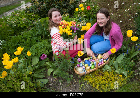 Easter egg hunt. Girls with their chocolate eggs and Spring flowers Stock Photo