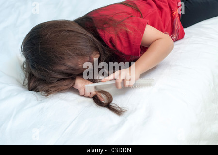 Girl brushing hair in bed Stock Photo