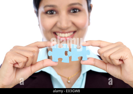 Young Indian business woman joining two jigsaw puzzle pieces against white background Stock Photo