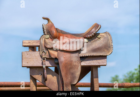 Leather horse saddle displayed on a stand against blue sky Stock Photo