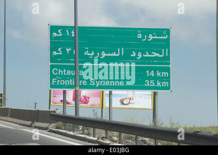 Beirut Lebanon. 30th April 2014. A  sign on the Beirut Damascus highway written in French and Arabic language points the distance to the Syrian border. The violence and conflict in neighbouring Syria has affected Lebanon's tourism as tourist stay away. The Foreign Office has advised against all but essential travel as the Syria's civil war spills over Stock Photo