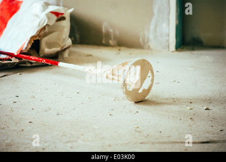 Home repair concept with dirty room floor and mixer instrument in plastering for renovation Stock Photo