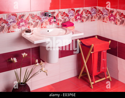 detail of a modern bathroom with floral motif tiles and accessories in red Stock Photo