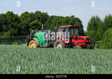 farm machinery tractor with long black sprayer working in field Stock Photo