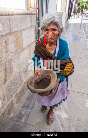 Bolivian woman beggar holding an empty hat out for money on a sidewalk in the central part of the city of Sucre. Stock Photo