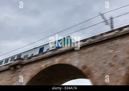 an old train crossing a bridge with a stormy sky Stock Photo