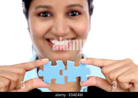 Young Indian business woman joining two jigsaw puzzle pieces against white background Stock Photo