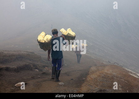 Men carrying baskets laden with blocks of sulfur, Kawah Ijen, Banyuwangi Regency, East Java, Indonesia Stock Photo