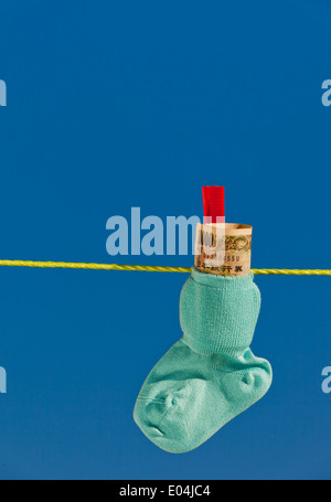 Baby socks on clothesline with yen to bank notes from Japan., Baby Socken auf Waescheleine mit Yen Geldscheinen aus Japan. Stock Photo