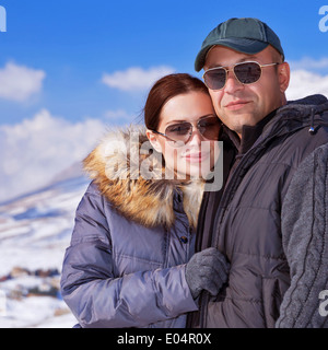 Closeup portrait of happy young family having fun in wintertime mountains, wearing fashionable sunglasses, travel and tourism Stock Photo