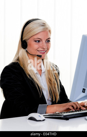 Young woman with Headset and computer with hotline., Junge Frau mit Headset und Computer bei Hotline. Stock Photo