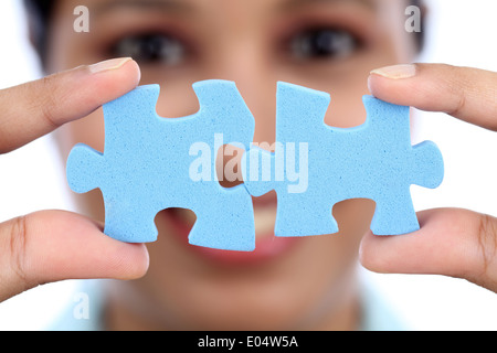 Young Indian business woman joining two jigsaw puzzle pieces against white background Stock Photo