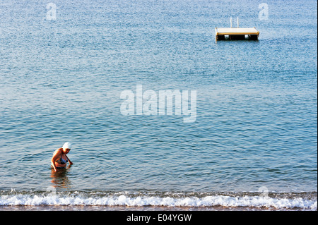 Europe, France, Alpes-Maritimes, Cannes. Old woman walking in water. Stock Photo