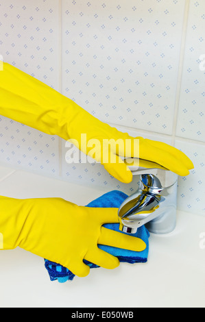 The wash basin of a bathroom is cleaned with latex to gloves., Das Waschbecken eines Badezimmers wird mit Latex Handschuhen gere Stock Photo