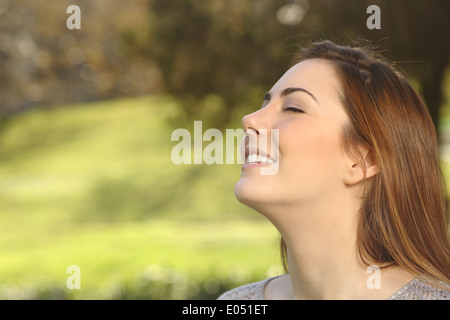 Beautiful happy smiling woman doing breathing deep exercises in a warmth park green background Stock Photo