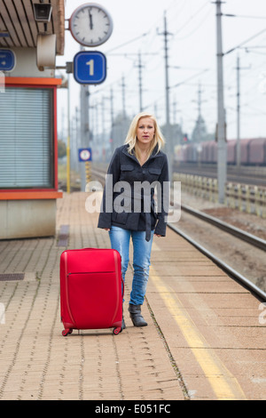 A young woman with suitcase waits on the platform of a railway station for her train. Delays, Eine junge Frau mit Koffer wartet Stock Photo