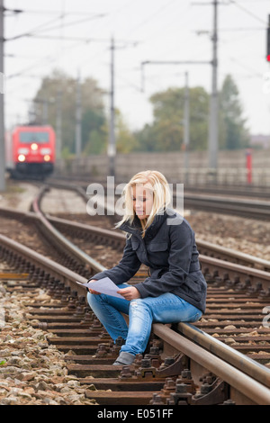 A young woman with suicide thoughts sits on a rail. If farewell letter holds in the hand and thinks about her suicide., Eine jun