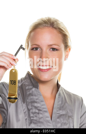 A young woman holds the key of a hotel of room in her hand. Rezeptionistin at the hotel, Eine junge Frau haelt den Schluessel ei Stock Photo